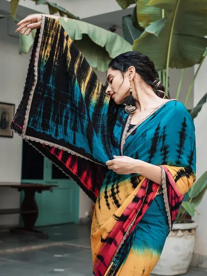 This shot highlights the beautiful pallu of the tie-dye saree. The model's pose elegantly displays the dramatic black and yellow pattern, showcasing the unique artistry of the garment.