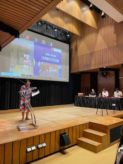 A participant reads from a text at the podium during the competition. The event is a celebration of literature and the spoken word.