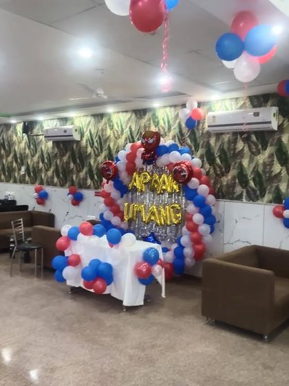 A Spiderman-themed birthday setup in a restaurant, featuring a balloon arch over a table and foil letters spelling the name.