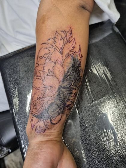 An in-progress shot of the floral cover-up, showing how the dark leaves are filled in first to effectively block out the old tattoo.