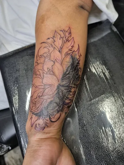 An in-progress shot of the floral cover-up, showing how the dark leaves are filled in first to effectively block out the old tattoo.