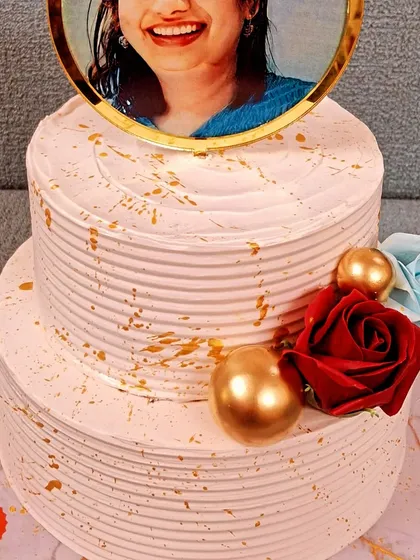 Make your celebration truly personal with a custom photo cake. This two-tier cake for a 50th birthday features an edible photo topper, elegant gold splatter, and floral accents, creating a beautiful and memorable tribute.