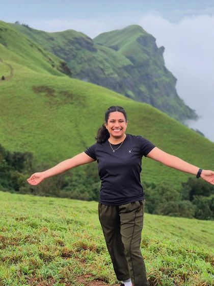 A happy trekker with her arms open, enjoying the freedom of the wide-open meadows on the Bandaje trek.