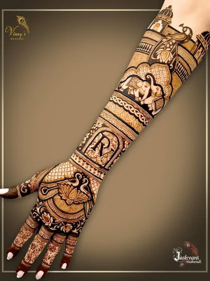 An elegant back-of-hand design personalized with the initial 'R'. The rest of the arm features classic wedding motifs like elephants and a bridal procession.