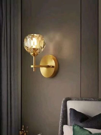 A classic wall sconce with a faceted crystal globe on a brass arm. This timeless design is perfect for adding a touch of elegance to a bedroom.