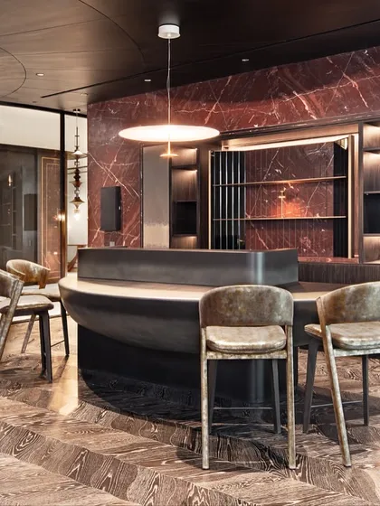 We designed this home bar to be an interactive and integrated part of the living space. The organically shaped bar counter, set against a dramatic Red Lavante stone wall, features a unique gradient finish. The custom bar stools, with their textured upholstery, are designed at a lower height to foster a more intimate and connected social experience.