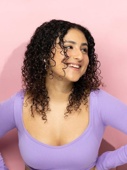 A candid and happy moment that showcases gorgeous, healthy curls. This lifestyle shot helps customers connect with the brand on an emotional level, seeing the joyful results of the products.