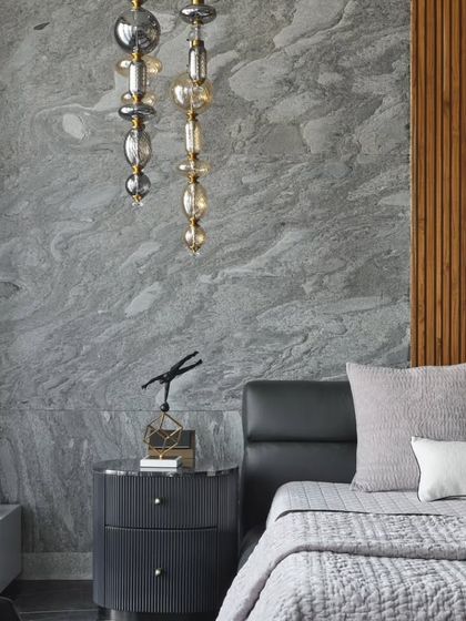 A close-up detail of the bedside, where a custom glass pendant light hangs over the nightstand. The combination of the rough stone wall, smooth wood paneling, and delicate lighting fixture highlights my approach of layering materials and textures.