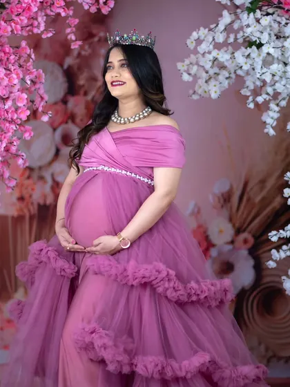 Surrounded by blossoms. This beautiful portrait places the mom-to-be in a purple gown between walls of pink and white flowers, creating a lush, romantic, and celebratory atmosphere.