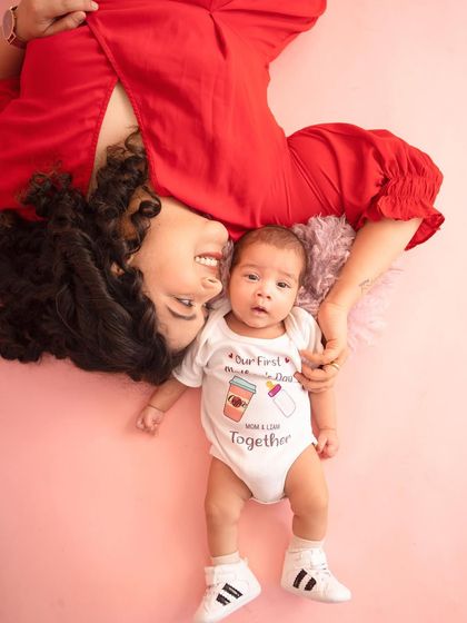 A fun and creative pose celebrating a baby's first Mother's Day. The custom onesie adds a personal and playful touch to this sweet memory.