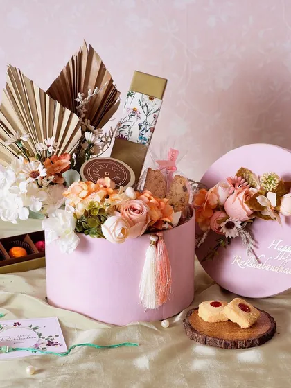 The Blossom Breeze Rakhi Hamper is a lovely pink box filled with brownie bites, chocolate bonbons, and almond biscotti.