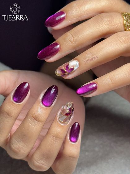 Shine that may cause jealousy. A bold set combining vibrant purple cat-eye nails with accent nails featuring hand-painted floral art.
