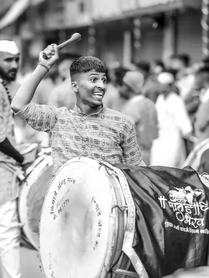 The black and white version of the joyful dhol player, emphasizing his expression and the dynamic pose.