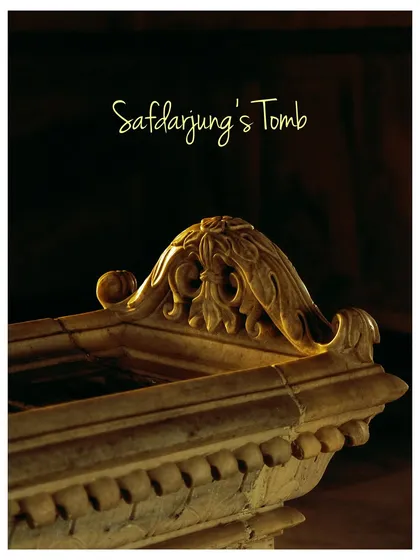 A close-up shot of the ornate marble carving on top of the cenotaph inside Safdarjung's Tomb. The elegant calligraphy and soft lighting highlight the delicate craftsmanship.