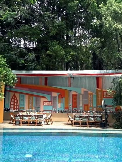 A wide shot of the vibrant Rajasthani-themed Mehendi setup by the pool, showcasing the colorful and unconventional backdrop we created for the food area.