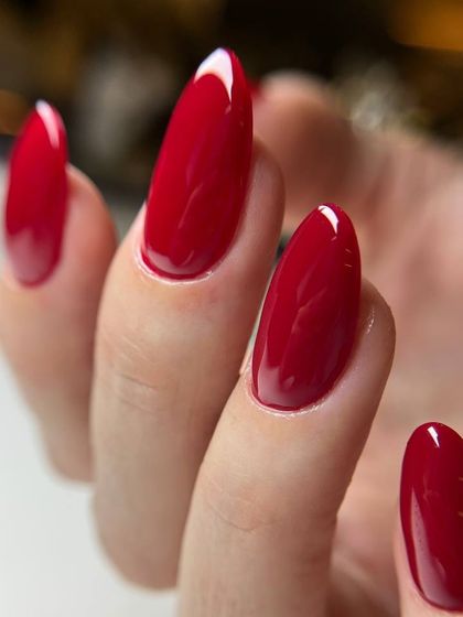 A deep, glossy red on long, almond-shaped nails. The shape and color combine for a look that is both classic and dramatic.