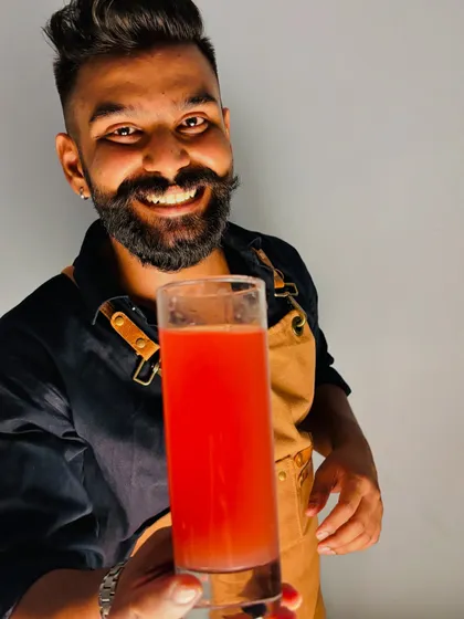 Holding up a freshly made cocktail, crafted with love and precision. This vibrant red drink shows the simple elegance we can bring to your event, whether it's a vodka-based classic or a custom creation.