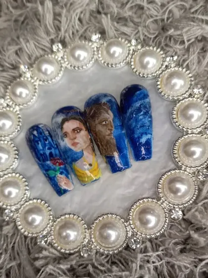 A full set of press-on nails dedicated to the Disney classic, Beauty and the Beast, featuring portraits of Belle and the Beast.