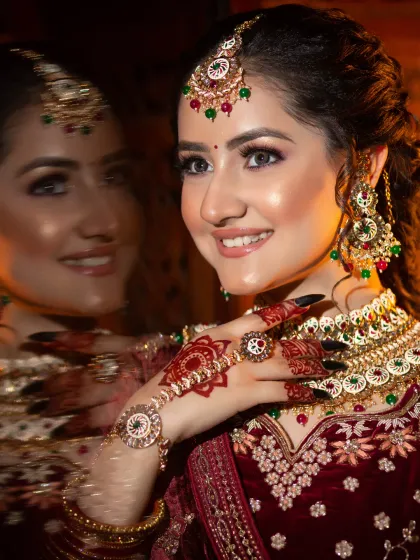 A creative shot of a bride in a maroon velvet lehenga. The reflection adds a dreamy quality to this classic, glamorous look.