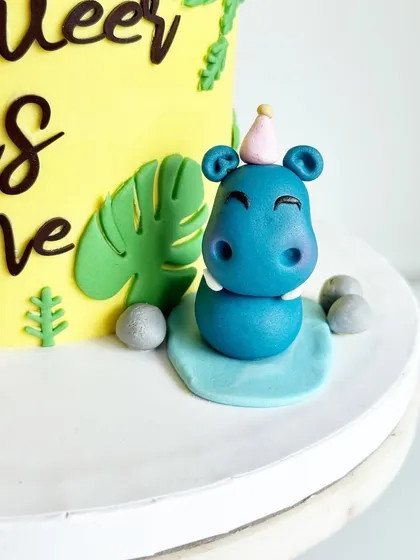 A smiling hippo topper, ready for a party! These small details are what make a custom cake so memorable.
