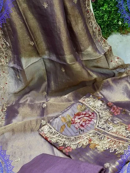 A rich purple dress material with a shimmering striped organza dupatta. The top features a digital floral print, creating a beautiful contrast of textures and patterns.