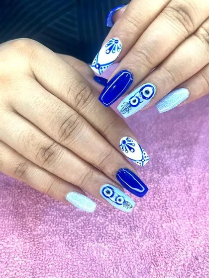 A bold blue and white set featuring "evil eye" designs and intricate patterns on long, coffin-shaped nails.