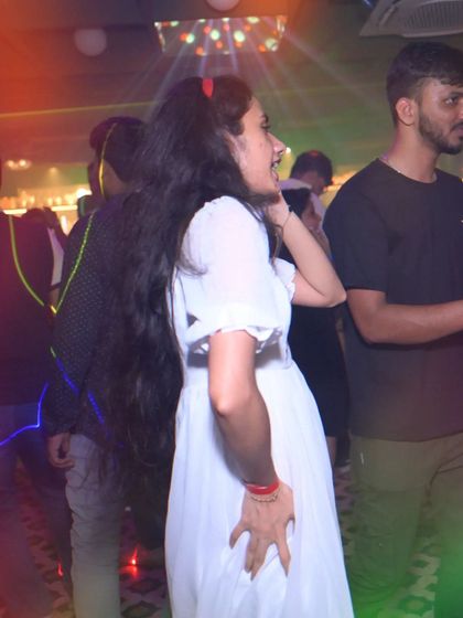 A candid moment of someone dancing and enjoying the music in a beautiful white dress.