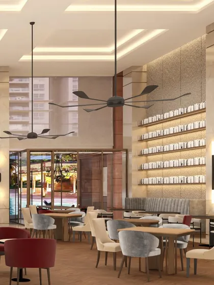 A close-up view of the dining area in the Elevate Clubhouse shows the interplay of textures and light. Backlit shelving, modern ceiling fans, and a mix of seating options create a layered, visually interesting environment that feels both elegant and comfortable.