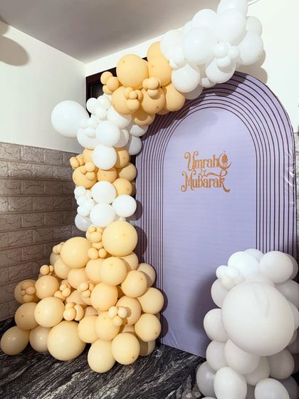 This angle highlights the texture and layering of the balloon arch against the custom printed backdrop for the Umrah Mubarak party.