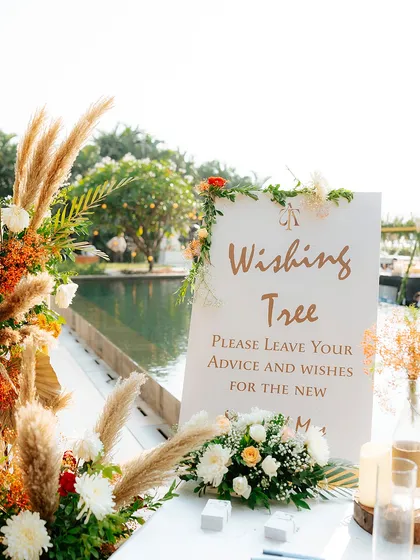 We love creating interactive elements like this "Wishing Tree," where guests can leave advice and wishes for the couple. This setup is by a beautiful poolside.
