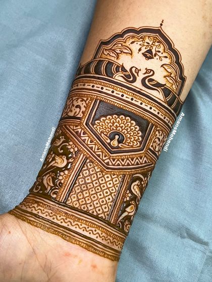 A close-up of an intricate arm band. The design features multiple layers of peacocks and geometric patterns, showcasing incredible detail and precision.