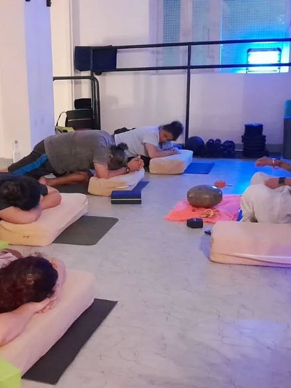 An instructor guides students through a restorative Yin pose, holding space for them to relax and release.