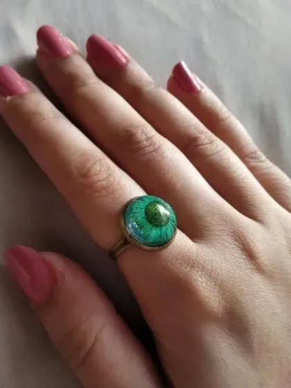This ethnic ring features a vibrant green flower preserved in resin. The simple, adjustable band makes it easy to wear, adding a pop of color to your look.