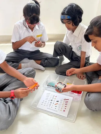 A team of girls from Sadhu Vaswani International School examines their LEGO pieces, preparing to build their creation.