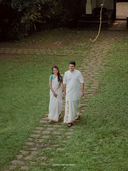 A wide shot of the couple walking on a stone path in a lush garden, a serene and romantic moment.