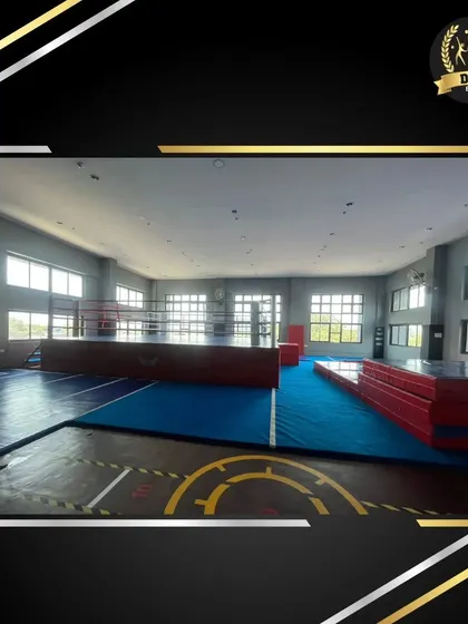 The expansive action training floor at Fly Zone, featuring a boxing ring in the background. The open layout provides ample space for various training drills and group classes.