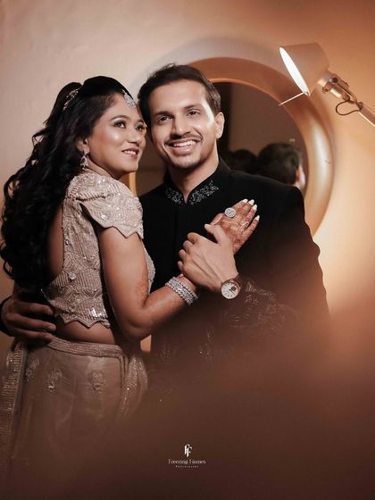 A happy, smiling portrait of the couple, with the bride showing off her engagement ring.