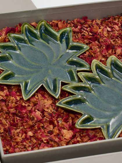 Two of our green lotus trinket plates nestled in a gift box filled with fragrant dried rose petals. We take great care in our packaging to ensure the unboxing experience feels truly special.