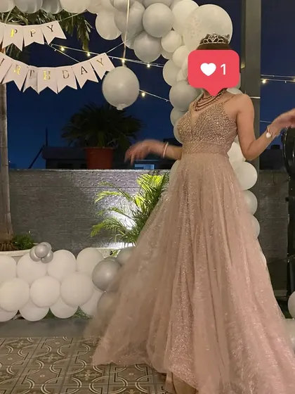 A birthday girl looking like a princess in her gown. The white balloon arch and 'Happy Birthday' banner provide a simple yet elegant backdrop for her special day.