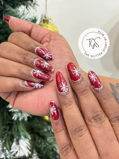Getting into the festive spirit with these sparkling red glitter nails. Each nail is adorned with a delicate, hand-painted white snowflake, making it the perfect manicure for the holiday season.