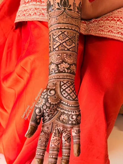 A close-up of the intricate patterns on the palm and forearm of a Rajasthani bridal design, featuring lotus motifs and geometric fills.