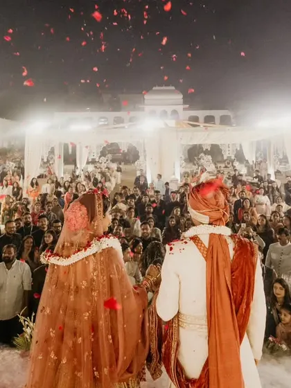 The couple standing before their guests during the ceremony. The shower of rose petals from above creates a beautiful and blessed moment.