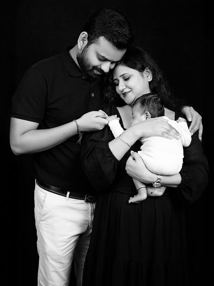 A new family of three. This black and white portrait beautifully captures the tender moment of parents admiring their newborn baby.