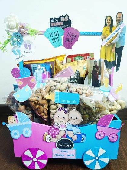 This baby shower hamper is designed to look like a little train, filled with dry fruits and snacks for the parents-to-be. I love adding personal details like a photo of the couple.