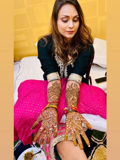 The bride-to-be posing with her full bridal mehndi. The design is intricate and extends up her arms, perfect for her special day.