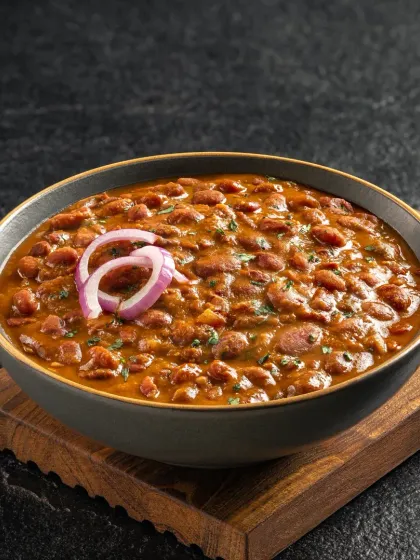 A comforting bowl of Rajma Masala. The deep red color of the gravy and the simple onion garnish make this dish look authentic and homemade.