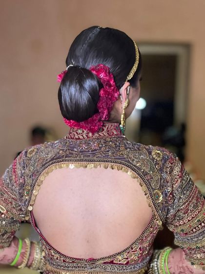 This is a very sleek and traditional bridal bun, also known as a juddha. I wrapped it with a string of pink flowers to match the bride's ornate lehenga.