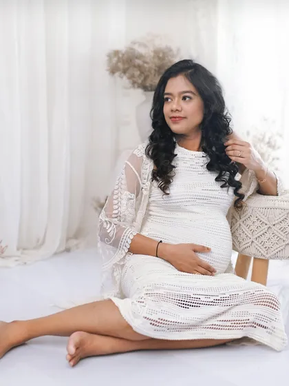 A relaxed, seated portrait on the floor. The addition of a lace shrug adds texture and detail to her outfit in this bohemian inspired white studio setup.
