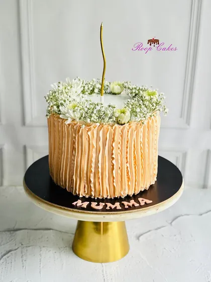 A touch of elegance in every layer. This cake for 'Mumma' features soft peach ruffles and is crowned with delicate baby's breath.