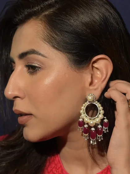A model wears a pair of magnificent pearl and ruby chandelier earrings, a design that exudes traditional grandeur and opulence, perfect for ceremonial occasions.